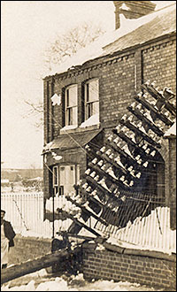 Photograph showing telegraph pole resting on house