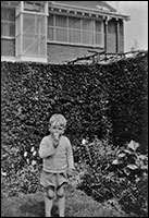 David aged about 6 in the garden, the pigeon loft in the background