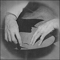 John White's hands cutting leather